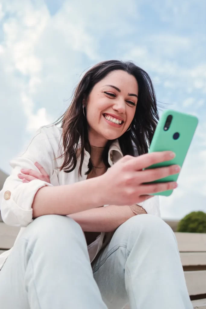 smiling-woman-using-phone-outside-on-sunny-day-2026-01-09-06-41-52-utc